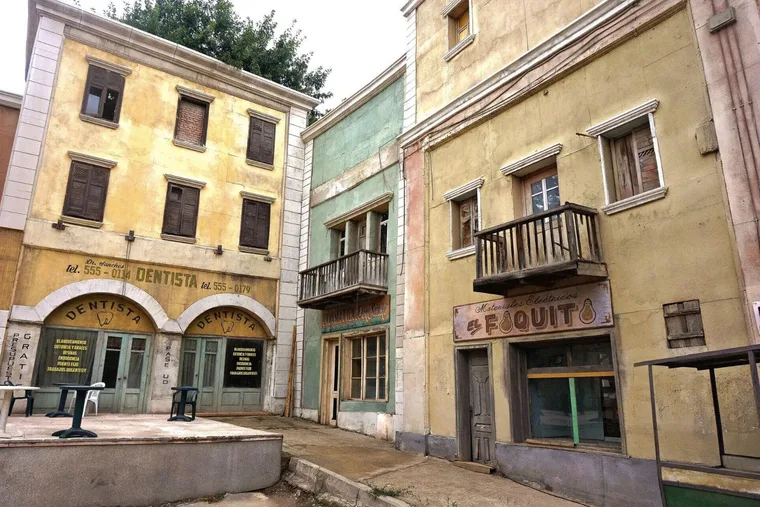 Plaster shopfronts with wooden balconies and painted signs on a standing street set near Sofia