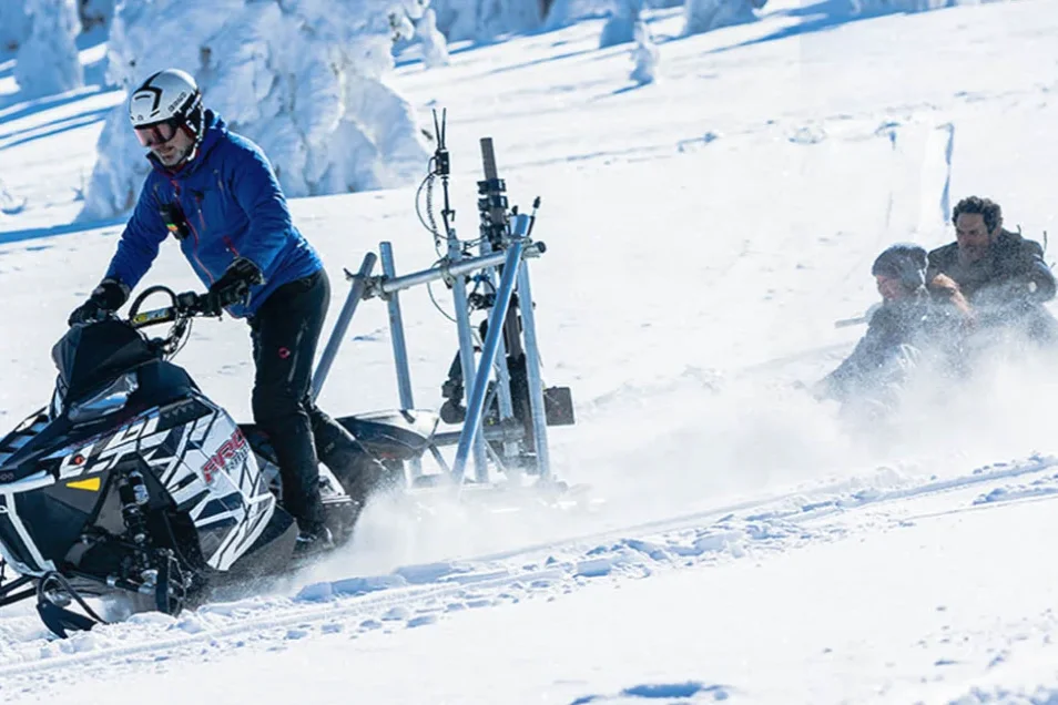 Snowmobile towing a camera rig on skis while filming a winter action sequence