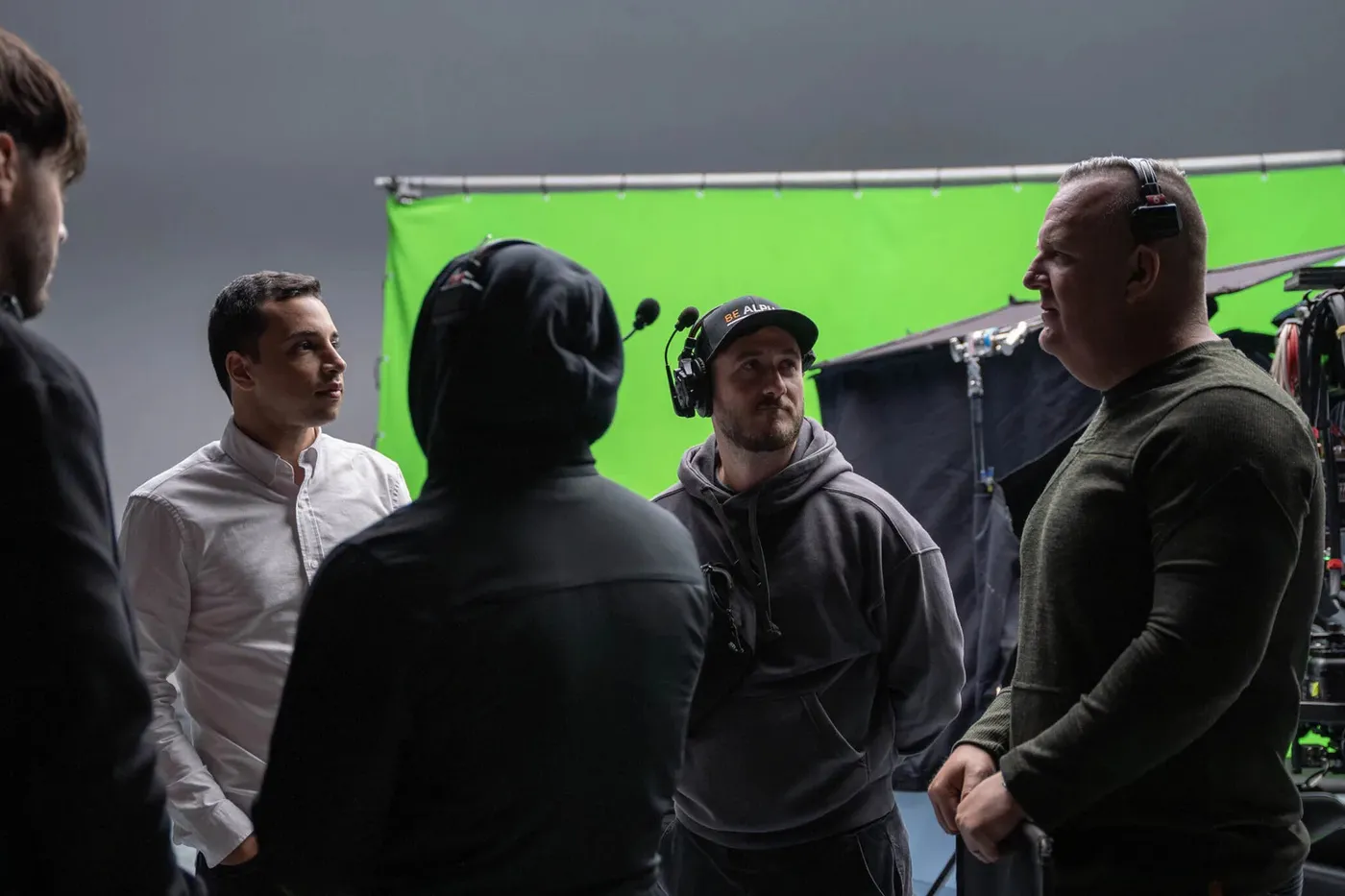 Production crew in discussion on a green screen stage during a commercial shoot